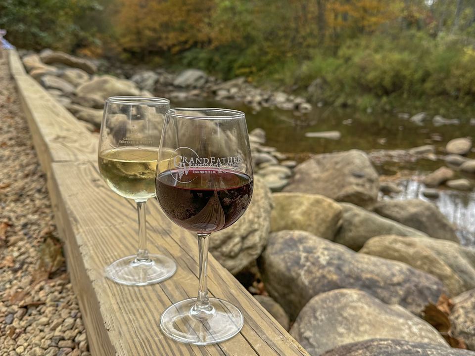 Two glasses of wine on a rail beside the river at Grandfather Vineyard